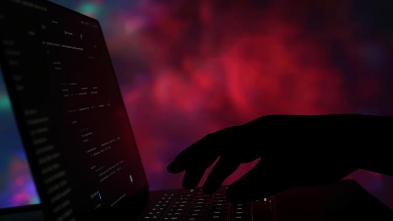 Code displayed on a computer screen with a silhouetted hand typing