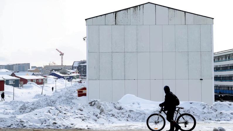 People pass buildings with social housings with an Inuit mural in Nuuk