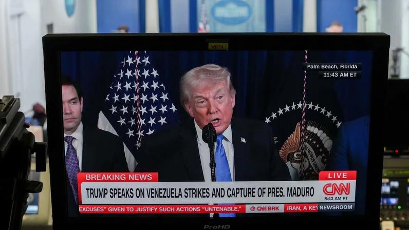 Televisão transmite a entrevista coletiva de Donald Trump sobre o ataque à Venezuela e a captura do seu líder, Nicolás Maduro, neste sábado (3) (Foto: Aaron Schwartz/Bloomberg)