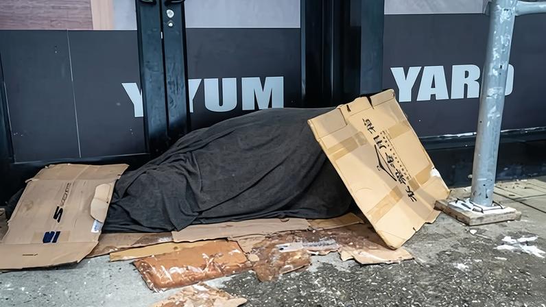 A person sleeps on a sidewalk in New York.