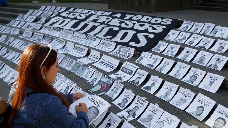 A woman arranges photographs of political prisoners during a protest called “Christmas Without Political Prisoners,” demanding their release after the disputed 2024 presidential elections as U.S. President Donald Trump’s administration increases pressure on Nicolas Maduro’s government, in Caracas, Venezuela, December 14, 2025.
