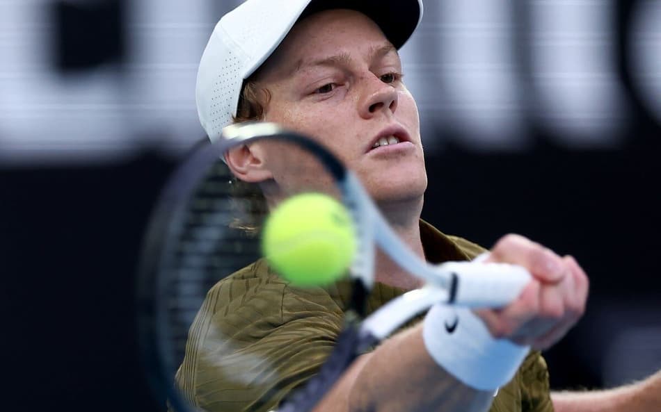 O italiano Jannik Sinner acelera a bola na partida contra o americano Ben Shelton no Australian Open (Foto: IZHAR KHAN / AFP)