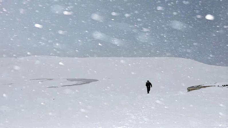 A man walks through the snowfall amid piled-up snow at the Tottori Sand Dunes in Tottori