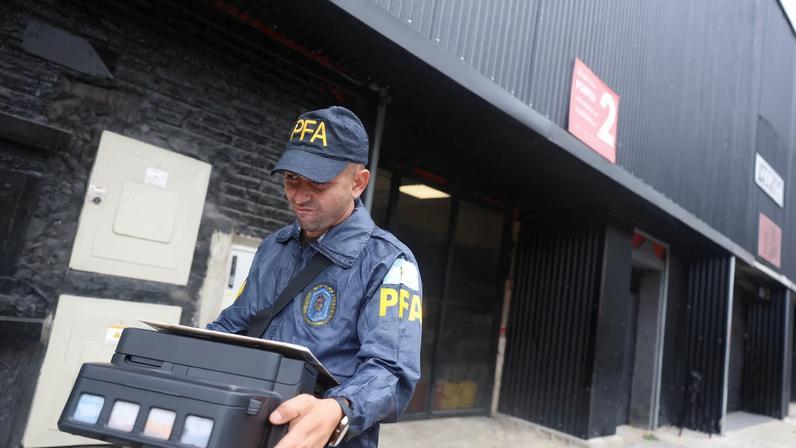 A member of the Argentine Federal Police walks after seizing a printer from the Claudio Chiqui Tapia stadium, which belongs to the soccer team Barracas Central, during a raid, amid an investigation into alleged money laundering involving the Argentine Football Association and a group of soccer clubs, according to local media, in Buenos Aires, Argentina, December 9, 2025.