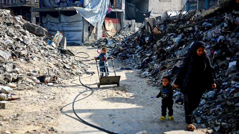 Palestinians walk past the rubble of residential buildings destroyed during the war, in Jabalia, northern Gaza Strip, January 6, 2026. REUTERS/Mahmoud Issa/File Photo