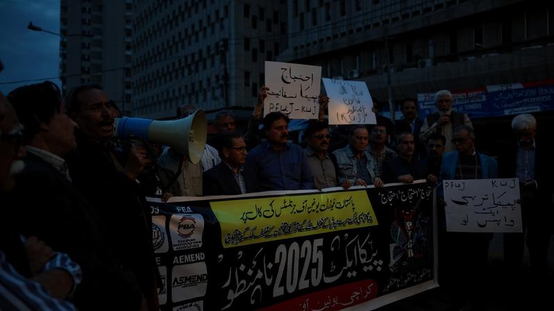 Journalists carry placards and a banner in a protest against what they call curbs on press freedom, in Karachi