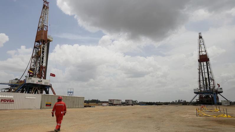 An oilfield worker walks next to drilling rigs at an oil well operated by Venezuela's state oil company PDVSA, in the oil rich Orinoco belt, near Morichal at the state of Monagas