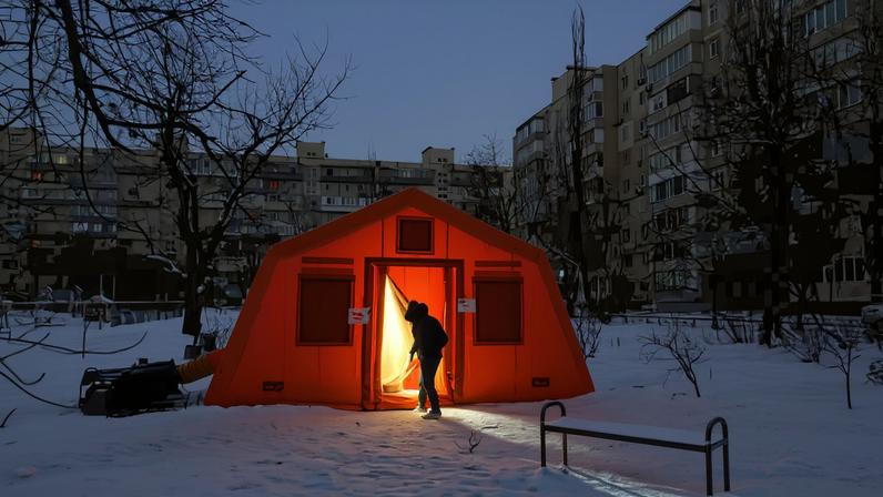 People enter a tent provided by emergency services for residents whose apartments are left without heating during sub-zero temperatures, amid Russia's attack on Ukraine, during a winter night in Kyiv