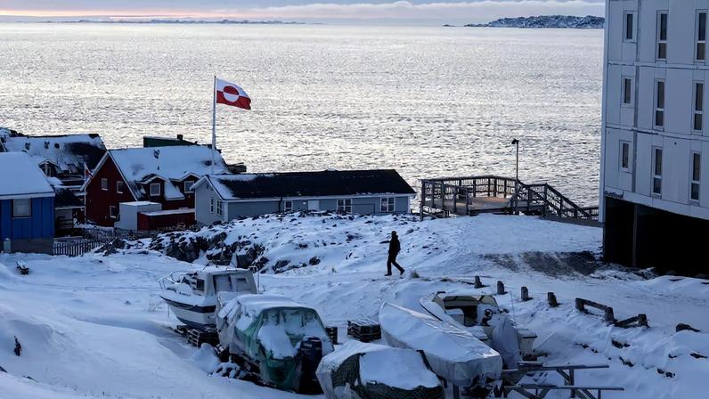 A Greenland flag flies as a man walks on the day of the meeting between top U.S. officials and the foreign ministers of Denmark and Greenland, in Nuuk