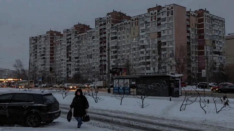 A person walks past darkened apartment buildings on a freezing day in Kyiv.