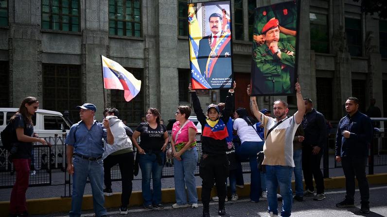 People hold photographs of Venezuela's late President Hugo Chavez and President Nicolas Maduro outside Vice-presidency building, after U.S. President Donald Trump said the U.S. has struck Venezuela and captured its President Nicolas Maduro, in Caracas, Venezuela, January 3, 2026. REUTERS/Gaby Oraa