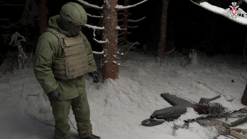 A Russian service member stands next to the remains of a drone, which, according to the Russian Defence Ministry, was downed during the repelling of an alleged Ukrainian attack on the Russian presidential residence in the Novgorod Region, in an unknown location in Russia, in this still image from a video released December 31, 2025.