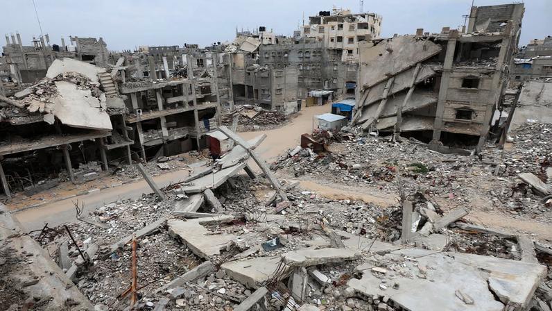 Palestinians walk surrounded by the rubble of houses destroyed in Israeli strikes during the war, in Khan Younis, southern Gaza Strip, January 22, 2026. REUTERS/Ramadan Abed
