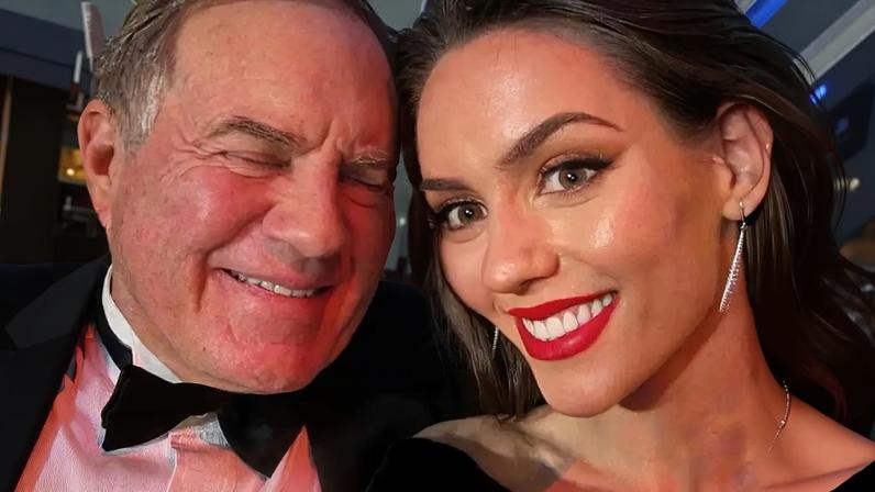 Jordon Hudson and Bill Belichick smiling together on the red carpet.