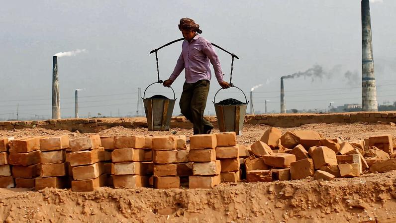 Smoke emits from chimney as Bangladeshi workers work at a bricks field on the outskirts of Dhaka, 2012.