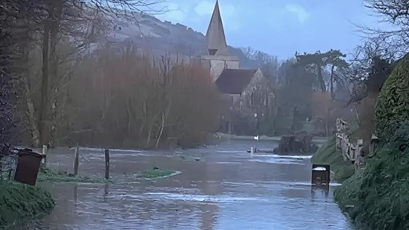Maggie Carden A flooded road with a large church in the background and greenery either side.