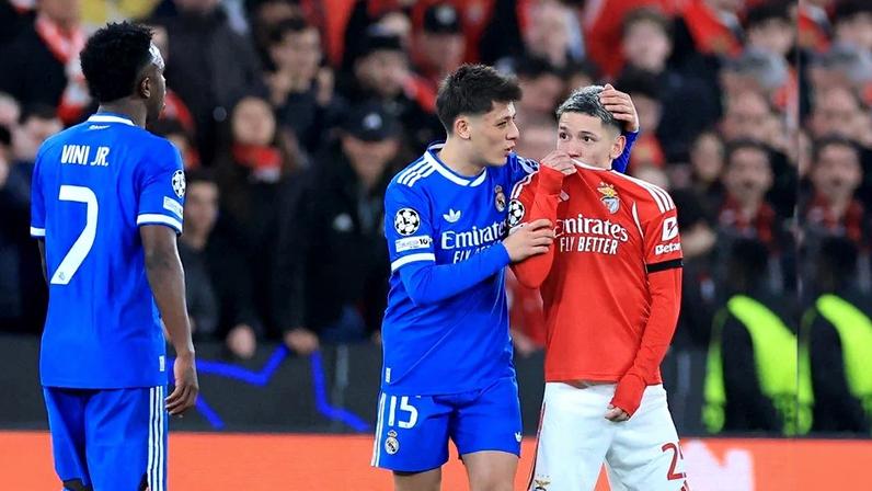 SL Benfica's Argentine forward #25 Gianluca Prestianni hides his mouth while arguing with Real Madrid's Brazilian forward #07 Vinicius Junior who complained about alleged racists insults during the UEFA Champions League knockout round play-off first leg football match between SL Benfica and Real Madrid CF at Estadio da Luz in Lisbon on February 17, 2026. (Photo by PATRICIA DE MELO MOREIRA / AFP)
