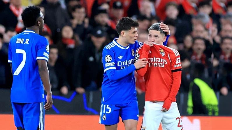 O atacante argentino do Benfica, número 25, Gianluca Prestianni, cobre a boca enquanto discute com o atacante brasileiro do Real Madrid, número 7, Vinicius Junior, que se queixou de supostos insultos racistas durante o jogo de ida da fase eliminatória da Liga dos Campeões. Foto: PATRICIA DE MELO MOREIRA / AFP