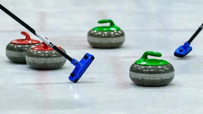Imagem de pedras de curling na pista de gelo.