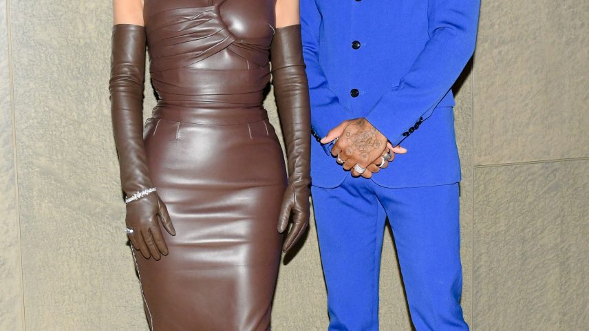 Kim Kardashian in a brown leather dress and Lewis Hamilton in a blue suit and turtleneck.