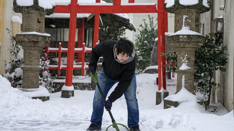 Homem limpa a neve na frente de templo em Tottori, Japão 25/01/2023. Mandatory credit Kyodo/via REUTERS