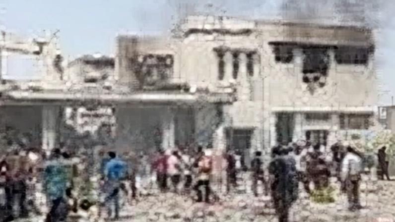 People in Iran gather around the remains of a burnt-out building