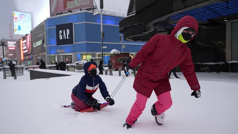 Dos jóvenes disfrutan de la nieve con un trineo, este lunes en Nueva York.