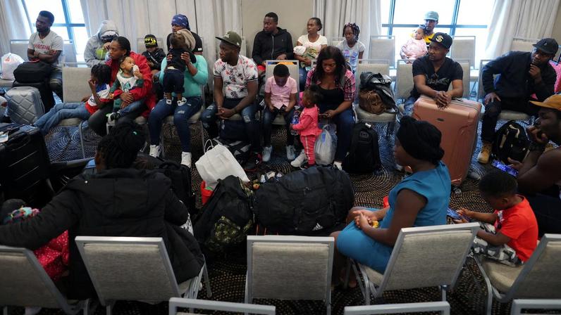 Immigrants from Haiti who recently arrived in Boston from other parts of the United States listen to instructions from representatives of La Colaborativa, a non-profit community services...