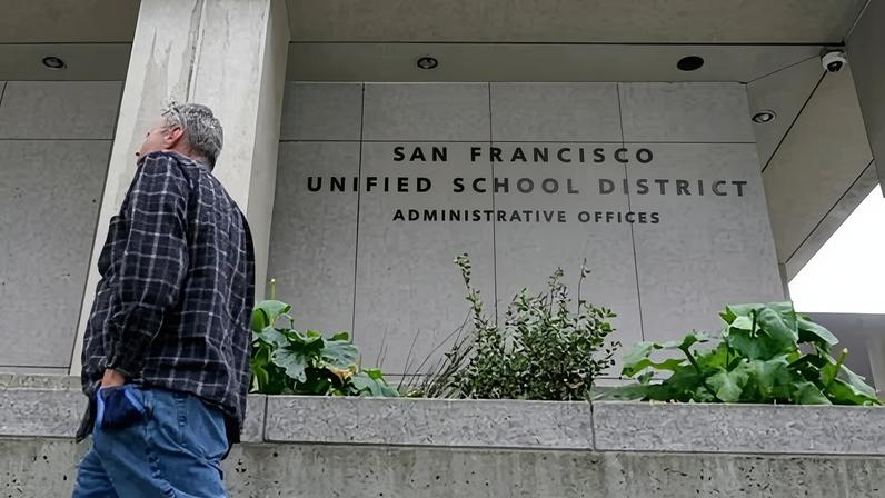 A pedestrian walks past a San Francisco Unified School District office building.