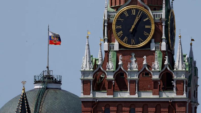 The Russian flag flies on the dome of the Kremlin Senate building behind Spasskaya Tower in Moscow