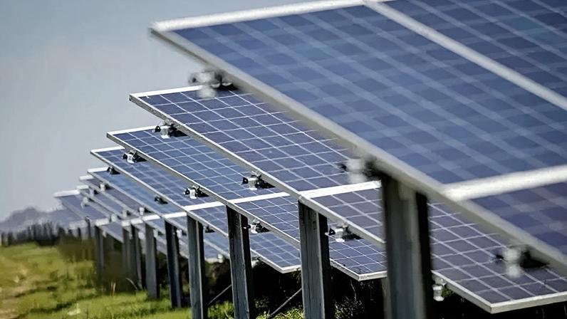 BBC A generic photo of about 40 large solar panels spanning out across a large green field.