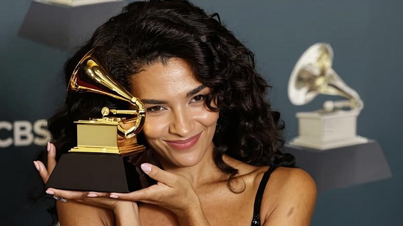Olivia Dean holds up her Grammy on the red carpet