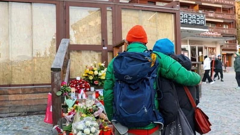 People stand by a makeshift memorial outside the Constellation bar in Crans-Montana.