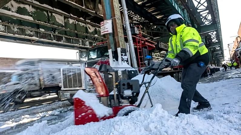 A man clears snow from the sidewalk on 24 February 2026 in Brooklyn, New York.