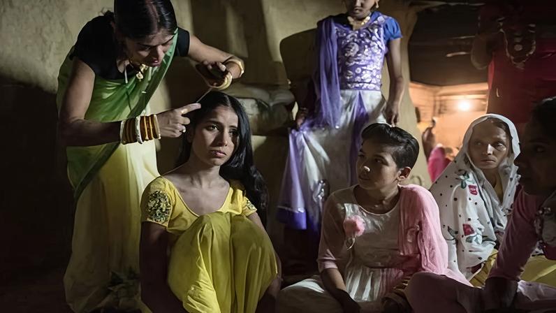 Surrounded by friends and relatives, Arti, 14, has her hair and makeup done as she prepares for her wedding ceremony.