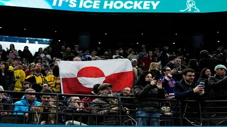 Fans hold the flag of Greenland ahead of Saturday’s preliminary round men’s ice hockey game between Greenland and the United States.