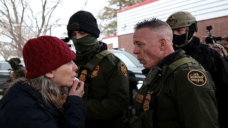 A woman blows a whistle in front of Greg Bovino in Minneapolis last week.