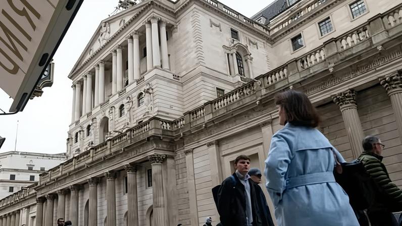 Woman in blue coat walks past Bank of England on Threadneedle Street