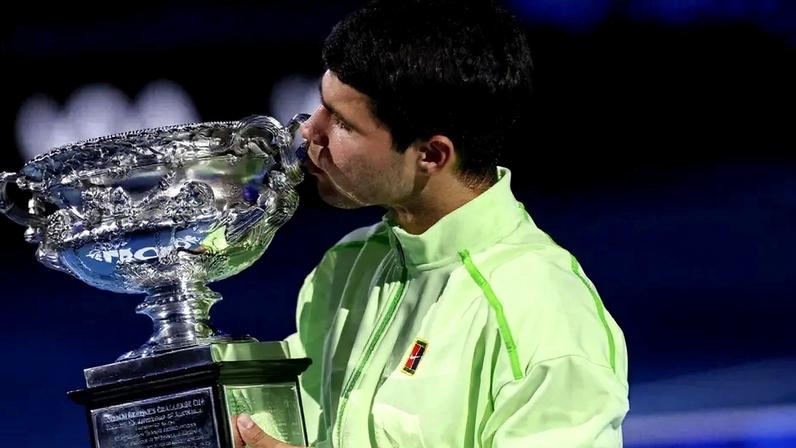 O espanhol Carlos Alcaraz beija seu sétimo Grand Slam, o primeiro no Australian Open (Foto: IZHAR KHAN / AFP)