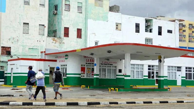 People pass in front of a gas station in Havana on Jan. 30.