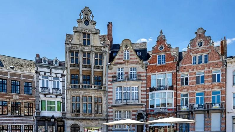 Casas históricas e cafés com mesas na calçada da Praça do Mercado, no centro histórico de Dendermonde/Termont, em Flandres