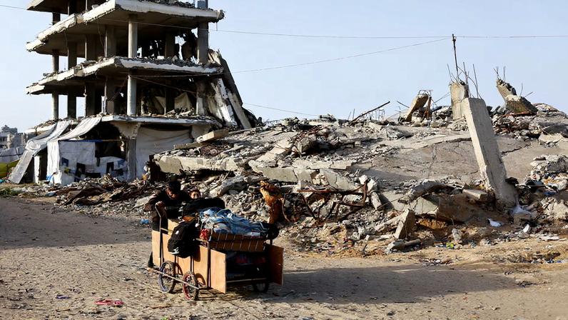 Palestinians push a cart past the rubble of residential buildings destroyed during the two-year Israeli offensives, in Gaza City, February 17, 2026. REUTERS/Mahmoud Issa