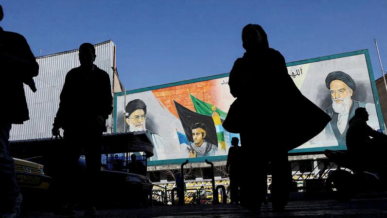 People walk near a mural featuring images of Iran's Supreme Leader Ayatollah Ali Khamenei and leader of Iran's 1979 Islamic Revolution Ayatollah Ruhollah Khomeini, on a street in Tehran, Iran, February 17, 2026.