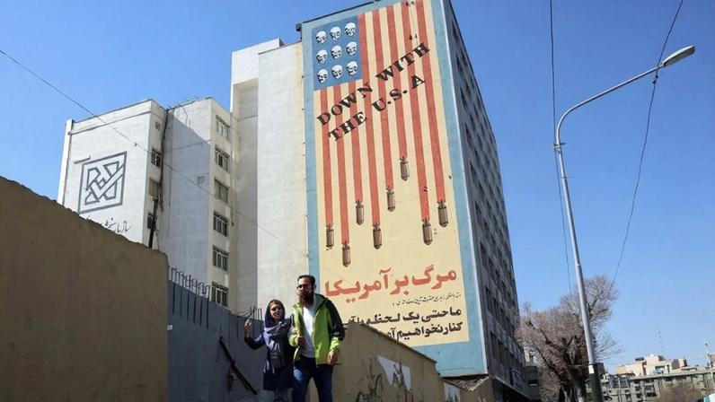 An Iranian couple walks past an anti-United States mural on a building in Tehran.