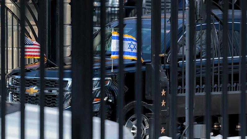 The car of Israeli Prime Minister Benjamin Netanyahu, bearing the U.S. and Israeli flags, enters a gate to the White House.