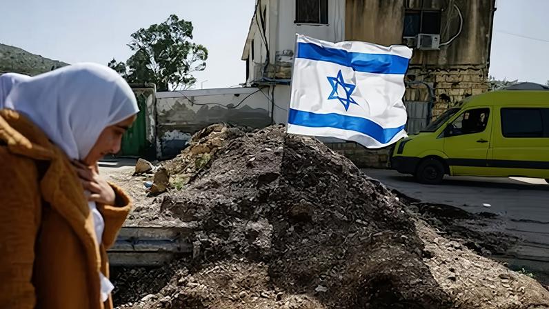 Una mujer camina junto a una barrera de tierra colocada recientemente por el ejército israelí en la entrada principal de Luban e-Sharkiya, entre Nablus y Ramala, en la Cisjordania ocupada, el pasado lunes.