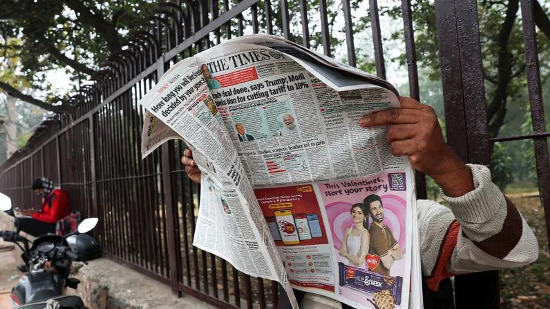 A man reads the latest edition of The Times of India newspaper, with the story on U.S. tariffs