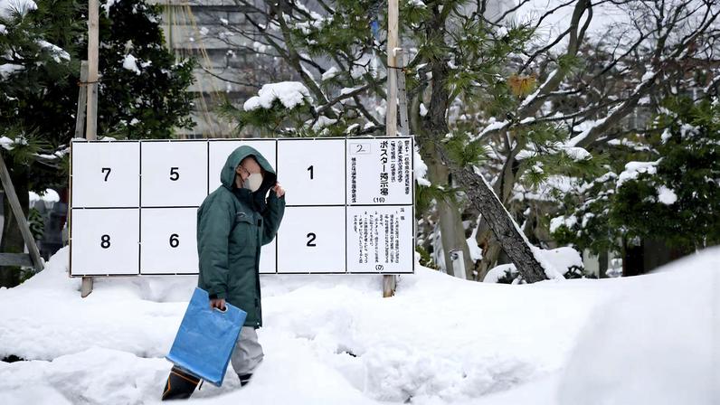 A person walks past a bulletin board for posters of candidates for the February 8 snap election, where snow has accumulated, in Fukui, Japan, January 26, 2026, in this photo taken by Kyodo. Mandatory credit Kyodo/via REUTERS