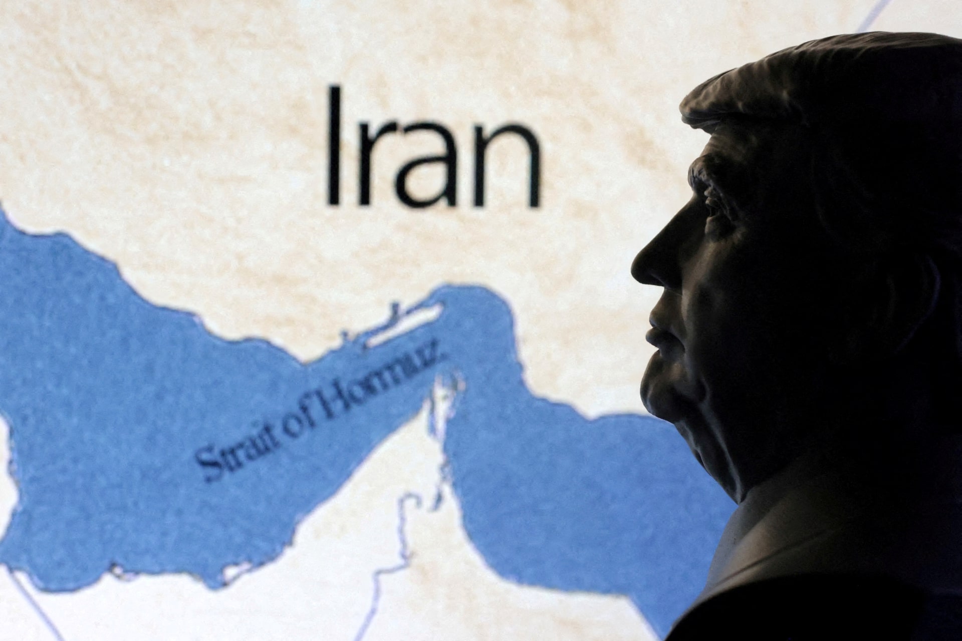 A map showig the Strait of Hormuz and Iran is seen behind a 3D printed miniature of U.S. President Donald Trump in this illustration taken June 22, 2025. REUTERS/Dado Ruvic/Illustration/File Photo