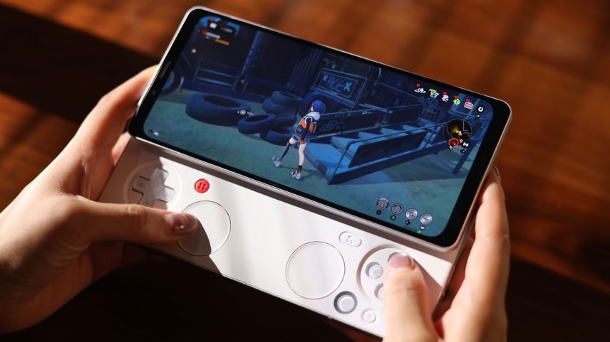 A person holds the Ayaneo Pocket Pay phone in two hands with its gaming controls extended.